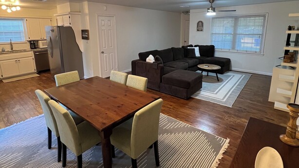 A spacious living area with a dining table, sofas, and a kitchen in the background. - Walking distance to the Stadium! Charming 3-bedroom house in lovely Norman (Norman)