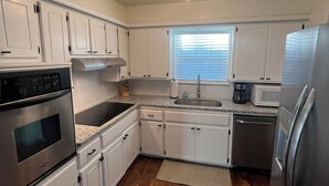 A modern kitchen with white cabinets, stainless steel appliances, and a wooden floor. - Walking distance to the Stadium! Charming 3-bedroom house in lovely Norman (Norman)