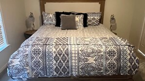 A bedroom with a large bed, wooden headboard, patterned bedding, two bedside tables with lamps, and a window with blinds. - Walking distance to the Stadium! Charming 3-bedroom house in lovely Norman (Norman)