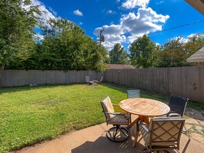 A backyard with a wooden table and chairs, a grassy lawn, and a wooden fence. - Walking distance to the Stadium! Charming 3-bedroom house in lovely Norman (Norman)