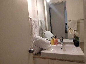 Een badkamer met een wastafel, toiletartikelen en een potplant.