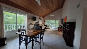 Un comedor con una mesa y sillas de madera, un sofá y vistas a través de un ventanal grande.