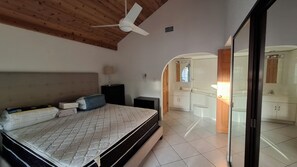 A bedroom with a bed, bedside table, lamp, and a ceiling fan. - 2 Bed Penthouse on Seven Mile Beach. Private Beach Cove, & 3 Pools! (#7) (Grand Cayman)