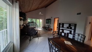 Un comedor con mesa y sillas de madera, un ventilador de techo y vistas al exterior.
