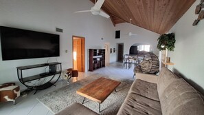 A living room with a flat-screen TV, a wooden coffee table, a sofa, and a ceiling fan. - 2 Bed Penthouse on Seven Mile Beach. Private Beach Cove, & 3 Pools! (#7) (Grand Cayman)
