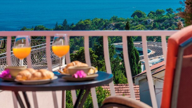 A balcony with a table set for breakfast, overlooking a coastal view with a distant island and a clear sky. - Hedera Estate, Villa Hedera XIX (Mlini)
