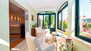 A bright room with a large window, a chair, a table with a book and a glass of orange juice, and a view of greenery outside. - Hedera Estate, Villa Hedera XIX (Mlini)