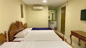 Habitación de hotel con dos camas, cabecera de madera, mesita de noche, televisor y aire acondicionado instalado en la pared.