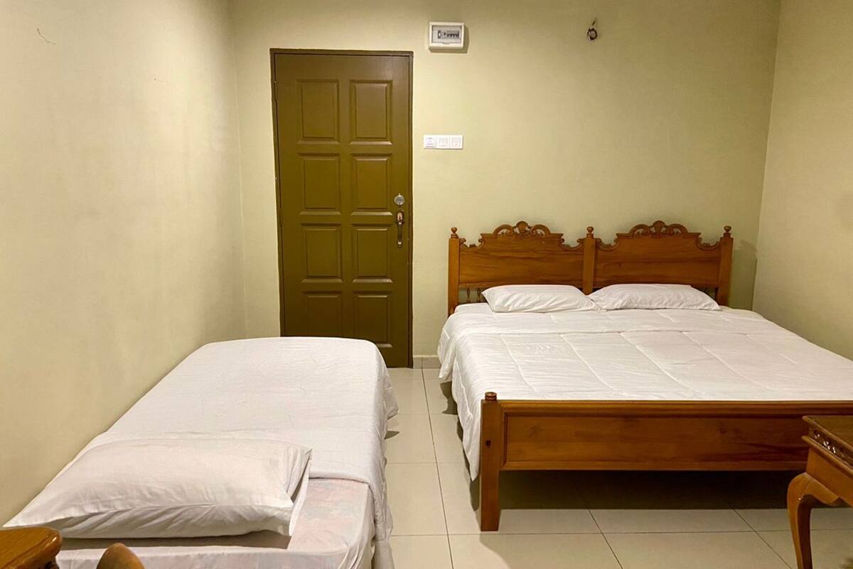 A bedroom with two single beds, a wooden headboard, a door, and a small table.