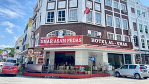 Un hotel con un cartel que indica 'Hotel Al-Umar' y el restaurante 'Umar Asam Pedas'.