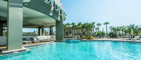 Une piscine avec des chaises longues et des palmiers en arrière-plan.