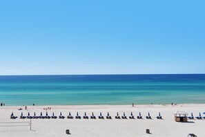 A beach with rows of sun loungers and umbrellas, a lifeguard tower, and a clear view of the ocean. - Laketown Wharf 838 (Panama City Beach)