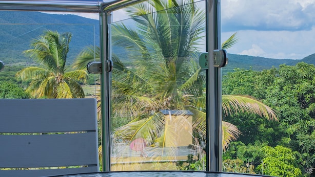 A round glass table with a metal frame, set against a backdrop of lush greenery and a mountainous landscape. - Villas Vallejuelo (Vallejuelo)