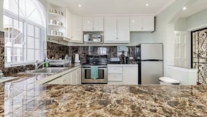 A modern kitchen with white cabinets, a marble countertop, a built-in oven, and a refrigerator. - Cozy 1-bedroom apartment in Ocho Rios stunning views of the Caribbean sea. (Ocho Rios)