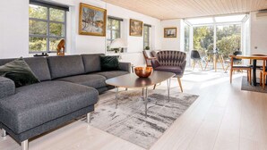 A modern living room with a grey sectional sofa, a round coffee table, and a patterned rug. - 4 Star Holiday Home in Jerup (Jerup)