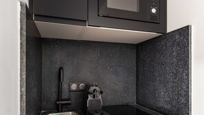 Una cocina moderna con un microondas negro, dos fregaderos y un rallador empotrado.