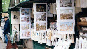 Un puesto en un mercado callejero con diversas postales e impresiones a la venta.