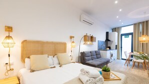 A modern hotel room with a large bed, a sofa, a dining area, and a kitchenette. - Travel Habitat Ruzafa Loft 1 (Valencia / València)