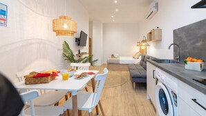 A modern kitchen with a washing machine, a dining area with a table and chairs, and a living area with a sofa and a TV. - Travel Habitat Ruzafa Loft 1 (Valencia / València)