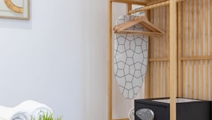 Un baño ordenado con un estante de madera que sostiene una toalla, un gabinete negro y una toalla con estampado geométrico colgada en la pared.