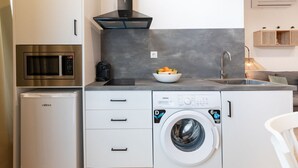 Una cocina compacta con microondas integrado, lavadora y lavaplatos.