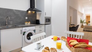 A modern kitchen with a washing machine, microwave, and a dining area with breakfast items. - Travel Habitat Ruzafa Loft 5 WIFI+AACC (Valencia / València)