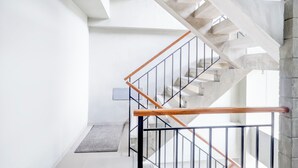 Een moderne trap met houten leuning en metalen spijbels, leidend naar een verdieping.
