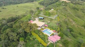 Vista aérea de una propiedad con piscina, una casa grande y follaje circundante.