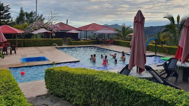 Un área de piscina con varias piscinas, sombrillas y sillas de descanso.