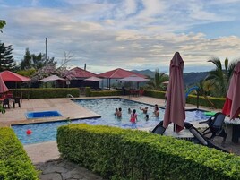 Una piscina al aire libre, sillones reclinables de piscina