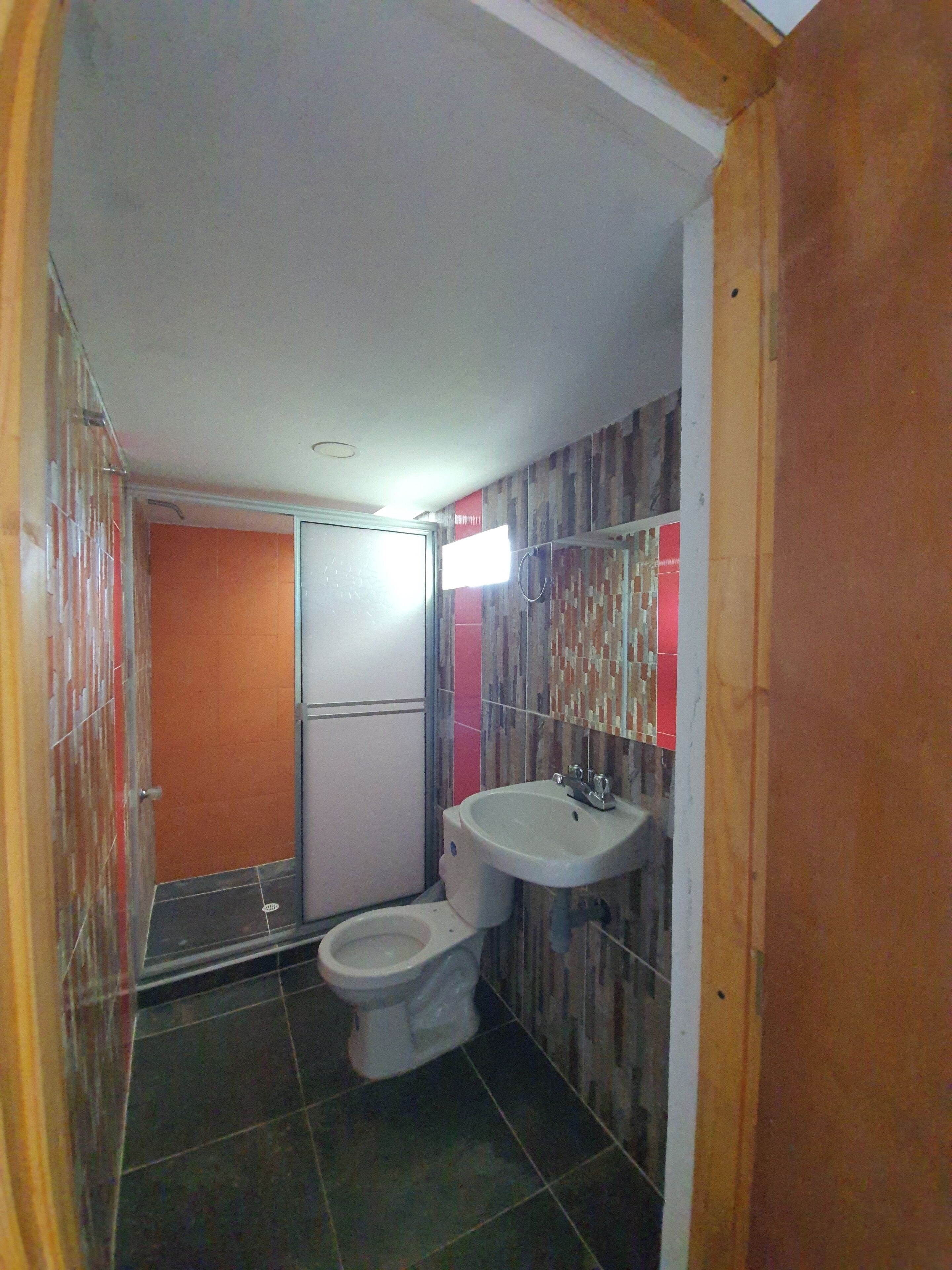 A small bathroom with a toilet, sink, and shower.
