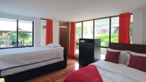 Habitación de hotel con dos camas, un armario y vistas a un jardín.