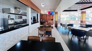 Une cuisine moderne dotée d’appareils électroménagers en acier inoxydable, de touches décoratives en bois et d’un coin repas avec des tables et des chaises.