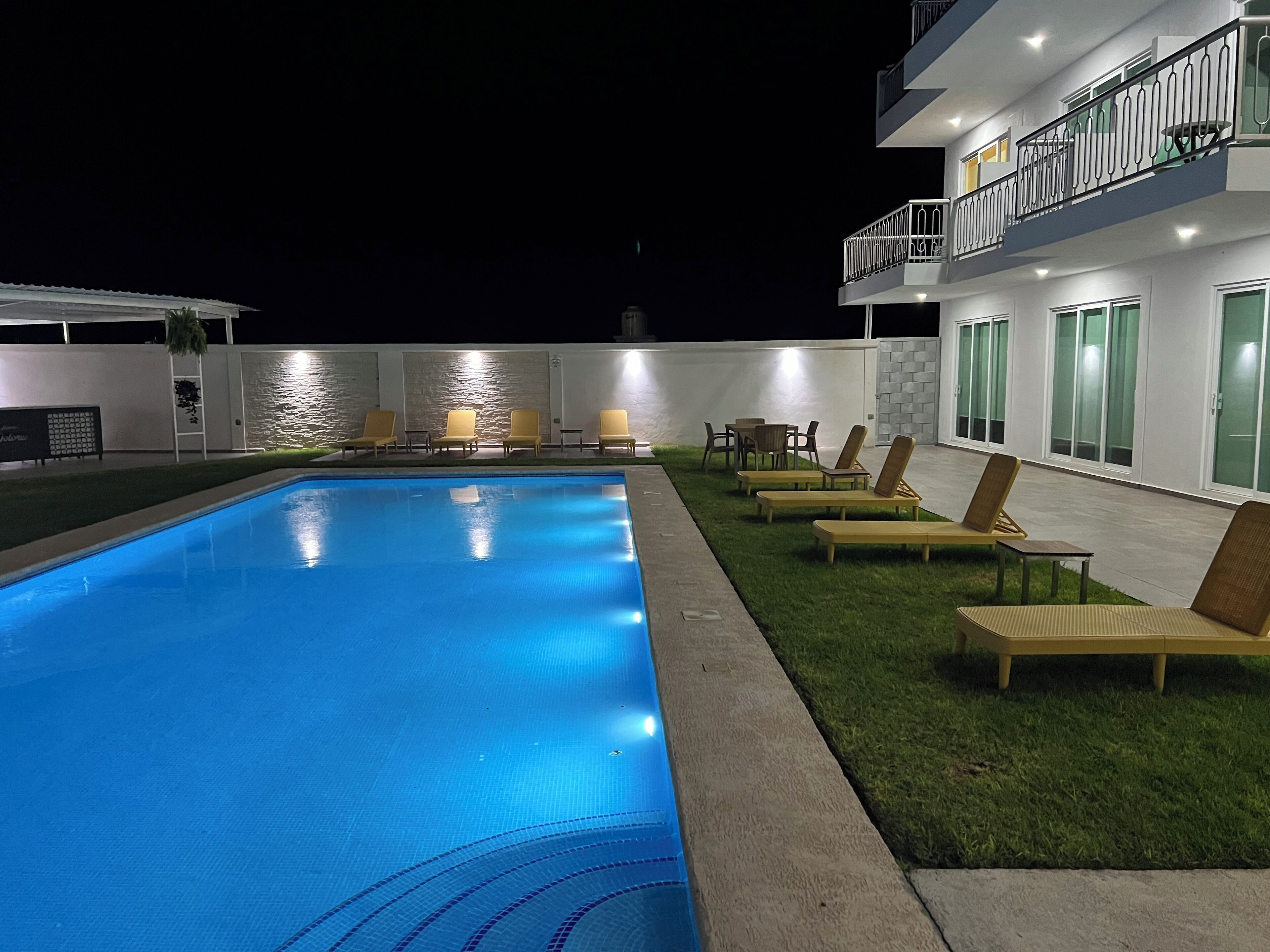 Una piscina con sillas de descanso y un edificio con balcones.