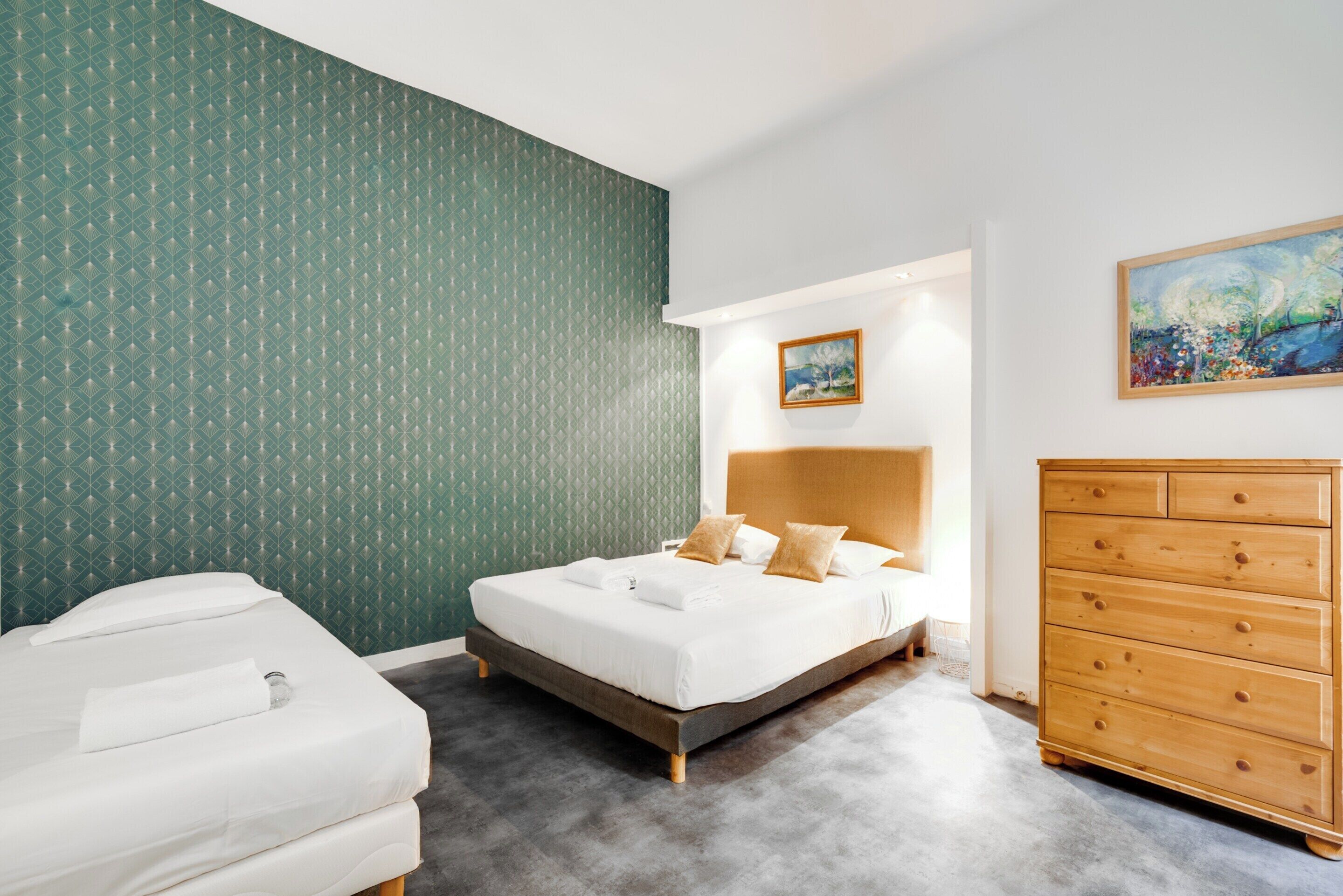 Una habitación de hotel con una cama, un aparador y un cuadro en la pared.