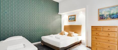 Una habitación de hotel con una cama, un aparador y un cuadro en la pared.