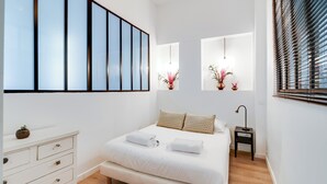 Un dormitorio moderno con una cama grande, un aparador y una mesita de noche con lámpara.