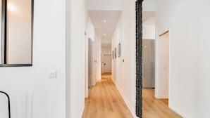 Un pasillo con suelo de madera, paredes blancas y un espejo de marco negro.