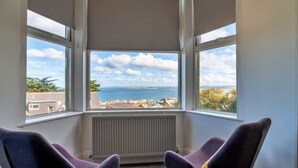 A corner room with two purple chairs, a view of the sea, and a white radiator. - No. 6 Porthgwidden (St Ives)