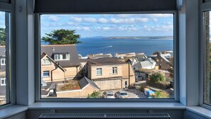 A view from a window overlooking a coastal town with houses and a body of water. - No. 6 Porthgwidden (St Ives)
