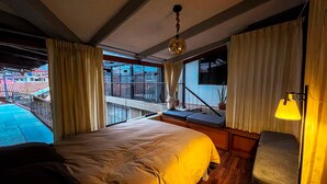 A bedroom with a large bed, a balcony with a view of buildings, and a window with curtains. - L'Aurora Residencial Cusco (Cusco)