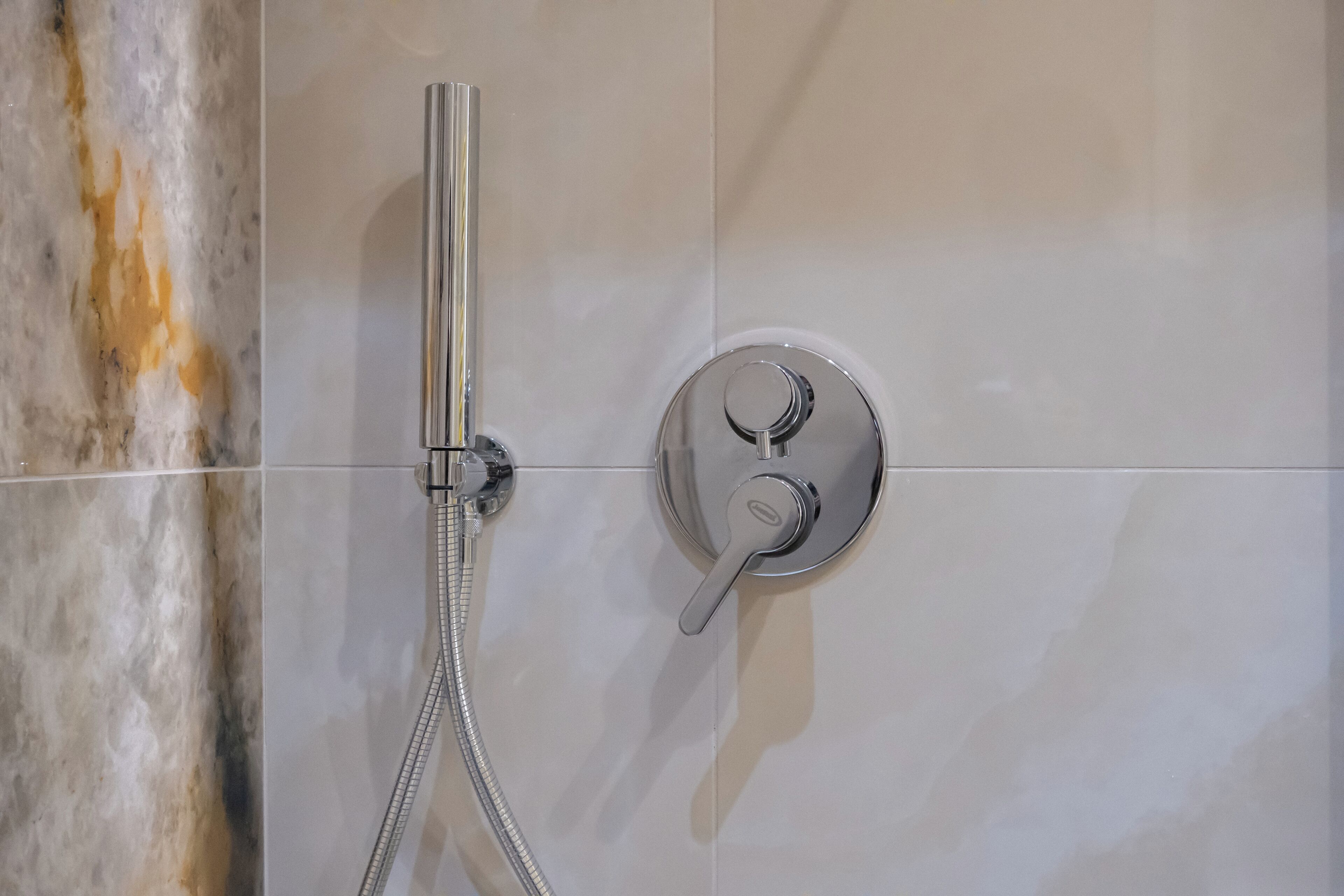 Ducha con cabezal de ducha de mano y control montado en la pared.