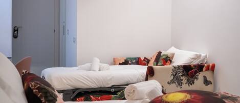 A hotel room with two beds, each with white linens and floral-patterned pillows.