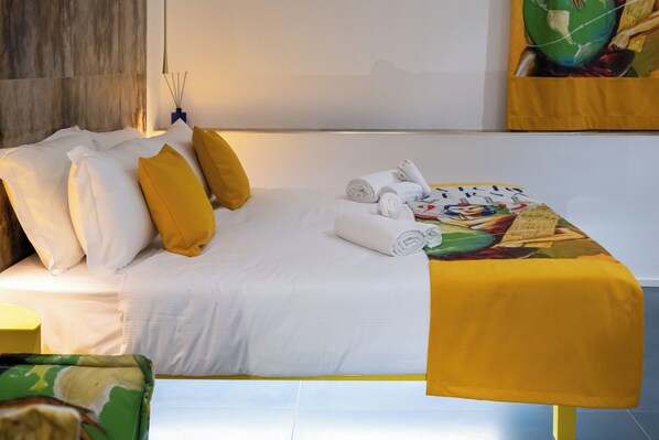 A neatly made bed with white and yellow pillows, a rolled towel, and a table with a yellow tablecloth. - Bhr Brancaccio 83 (Rome)