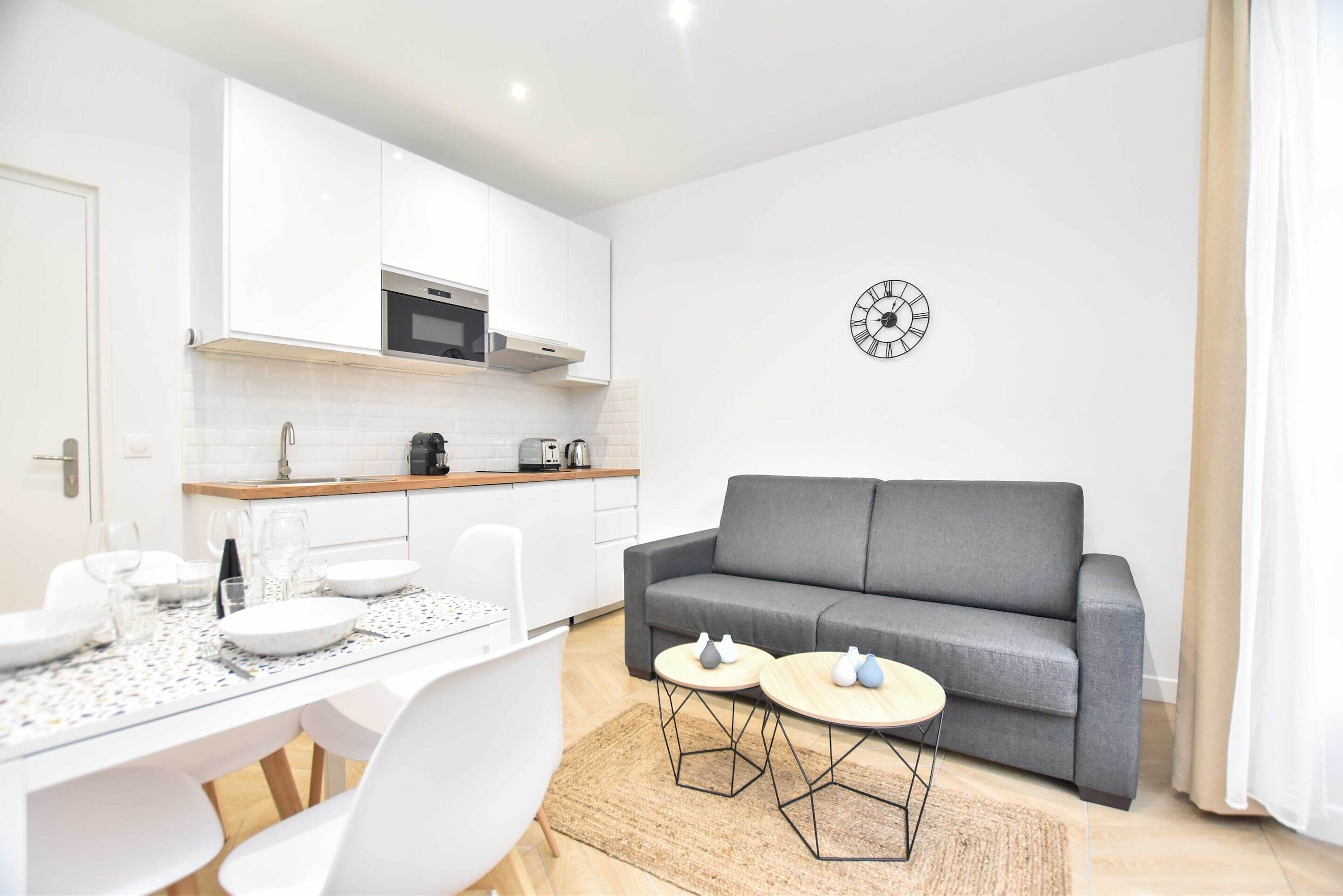 A modern kitchen with white cabinets, a microwave, and a clock on the wall.