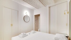 Una habitación de hotel con una cama grande, un espejo redondo y un armario.