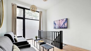 Una sala de estar moderna con un sofá gris, una mesita de centro y una escalera con barandilla negra.