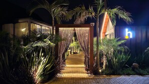 Un chemin menant à un bâtiment sur lequel on peut lire l’inscription « cabana », entouré de palmiers et de plantes.