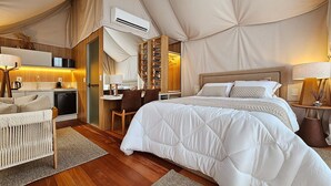 Un hébergement sous tente comprenant un lit, un bureau, une chaise et un porte-chaussures.