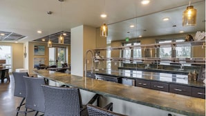A modern kitchen with a long counter, bar seating, and pendant lighting. - Landing | Incredible 2BD, Clubhouse, Pool (Portland)